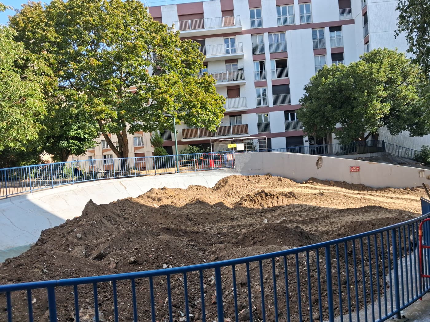 Espace public terrassé derrière ses garde-corps, immeubles en arrière-plan