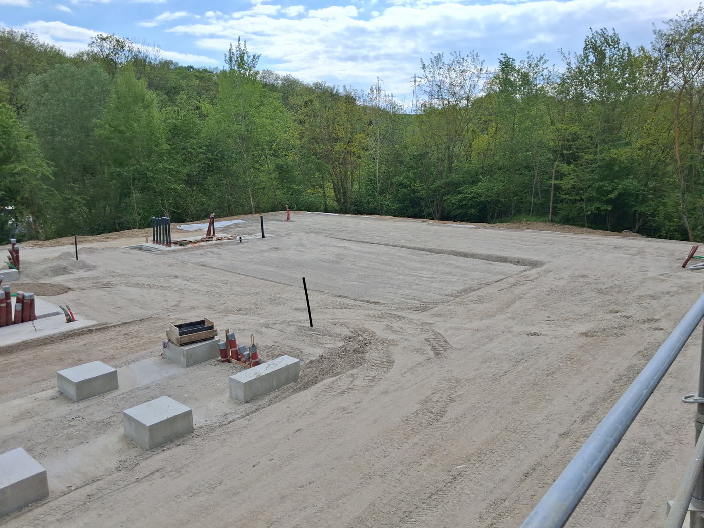 Plateforme en grave réglée, massifs béton en place, en lisière de bois