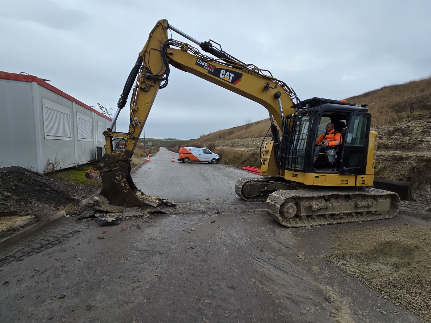 Pelle sur piste de chantier, bungalows de l'exploitant en arrière-plan